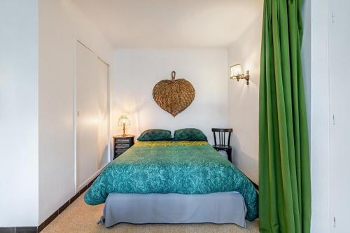 - une chambre avec un lit et des rideaux verts dans l'établissement Le Marignan- Studio plein centre, à Cassis