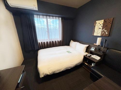 a hotel room with a bed and a window at Hotel Route Inn Osaka Izumi -Kishiwada Izumi Inter- in Izumi