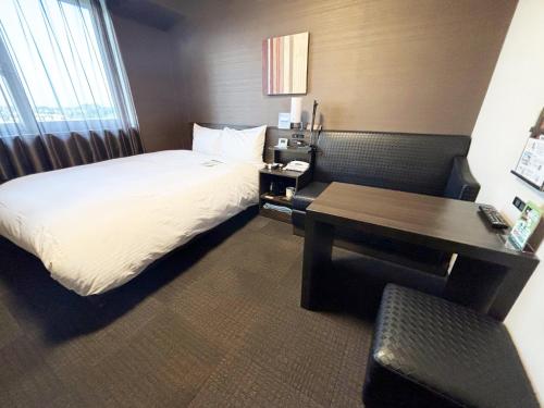 a hotel room with a bed and a desk at Hotel Route Inn Osaka Izumi -Kishiwada Izumi Inter- in Izumi