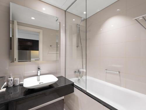 un bagno bianco con lavandino e vasca di Sunlit Studio Haven - Luxury Living in Majestine a Dubai