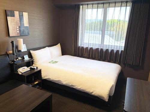 a hotel room with a bed and a window at Hotel Route Inn Osaka Izumi -Kishiwada Izumi Inter- in Izumi