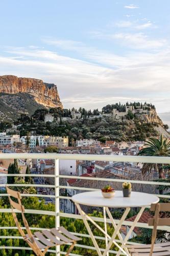 une table et des chaises sur un balcon avec vue sur une ville dans l'établissement Indigo, à Cassis