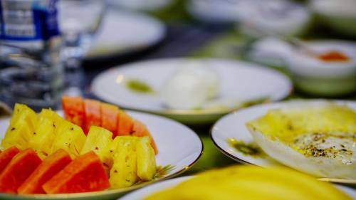 a table topped with white plates filled with fruits and vegetables at Sigiri SAAT Cabana in Sigiriya