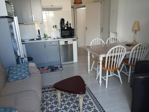 une cuisine et un salon avec une table et des chaises dans l'établissement Appartement tout confort hyper centre, à Royan