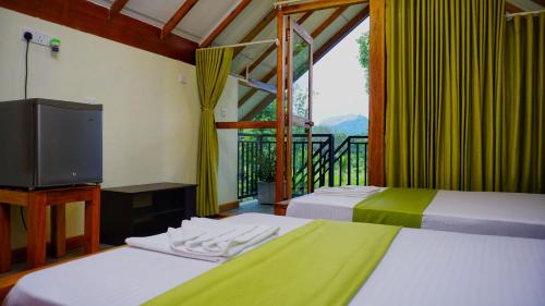 two beds in a room with a television and a balcony at Sigiri SAAT Cabana in Sigiriya