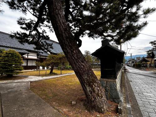a tree sitting next to a stone box next to a tree at 古民家ゲストハウス ナマケモノ in Ōno