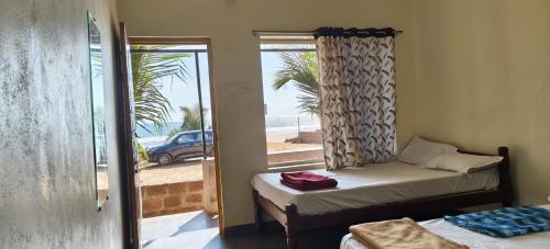 a room with two beds and a window with a view of the beach at Gokarna Govekar Sea Facing Rooms in Gokarn