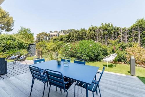 une table bleue et des chaises sur une terrasse en bois dans l'établissement L'Oasis Cassidaine - jardin 120m2, 2 places parking proche center et mer, à Cassis