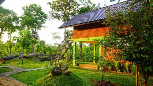 an orange building with a staircase in a garden at Sigiri SAAT Cabana in Sigiriya