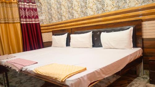 a bed with white sheets and pillows in a room at vaidehi homlee premium stay, 3kms from Shri Ram janmbhoomi, Ayodhya in Faizābād