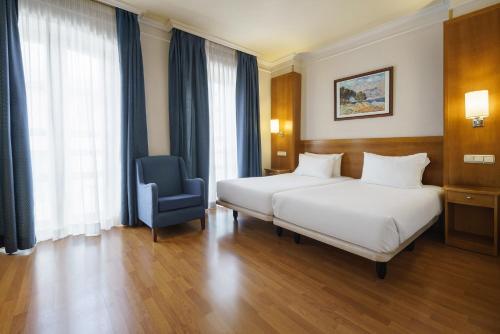a hotel room with two beds and a blue chair at Crisol Almería in Almería
