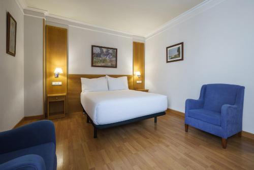 a hotel room with a bed and a blue chair at Crisol Almería in Almería