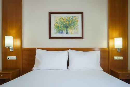 a bed with white pillows and a picture on the wall at Crisol Almería in Almería