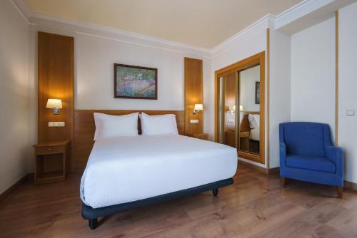 a bedroom with a white bed and a blue chair at Crisol Almería in Almería