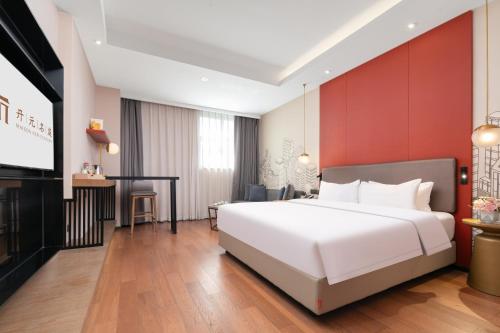 a bedroom with a white bed and a flat screen tv at Mansion New Century Hotel Chengdu Wuhou in Chengdu
