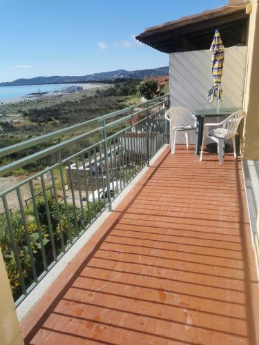 a deck with two chairs and a table on a house at La casetta sulla spiaggia in La Caletta