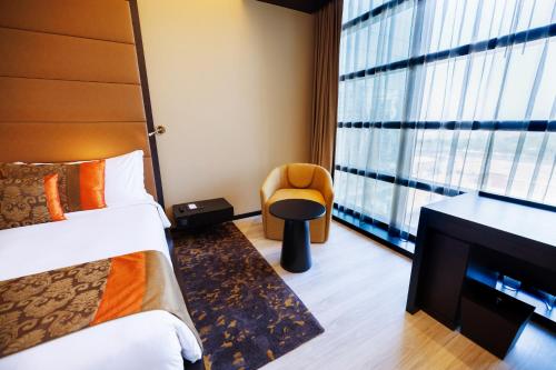 a bedroom with a bed and a chair and a window at Southern Sun Abu Dhabi in Abu Dhabi