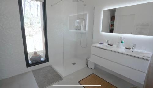 une salle de bain blanche avec un lavabo et un miroir dans l'établissement La Villa du Bout du Monde, Pool & Jacuzzi, à Soorts-Hossegor