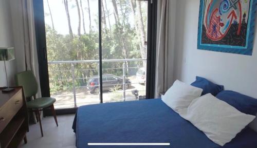 une chambre avec un lit bleu et une grande fenêtre dans l'établissement La Villa du Bout du Monde, Pool & Jacuzzi, à Soorts-Hossegor