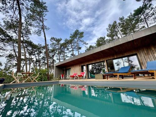une piscine avec des chaises et une maison dans l'établissement La Villa du Bout du Monde, Pool & Jacuzzi, à Soorts-Hossegor