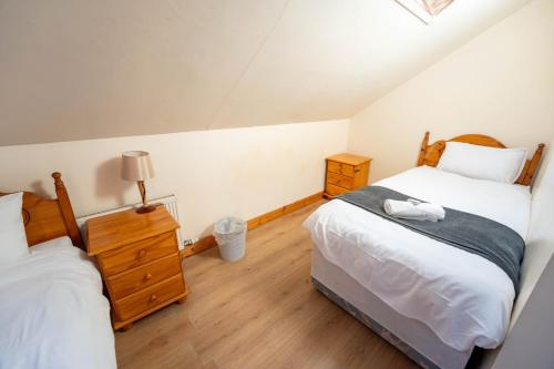 a bedroom with two twin beds and a night stand at Aras Ghleann Cholm Cille in Glencolumbkille