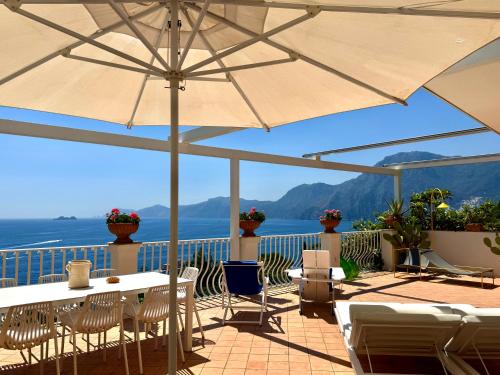 a patio with a table and chairs and an umbrella at Celebrity Suite - Big Terrace on the Sea in Praiano