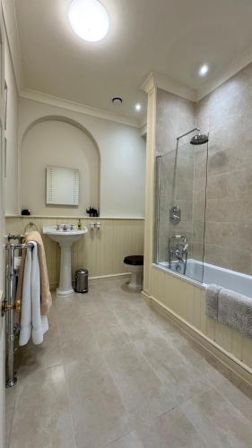 a bathroom with a shower and a tub and a sink at Uphill Manor Bed & Breakfast in Uphill