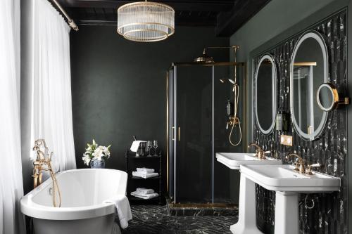 a bathroom with two sinks and a tub and two mirrors at Schloßhotel Althörnitz in Bertsdorf