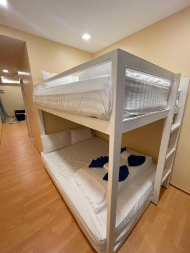 a bunk bed with white bunk beds in a room at High Lamoon in Sathani Khlong Rian