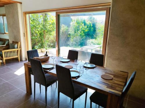 ein Esstisch mit Stühlen und ein großes Fenster in der Unterkunft Maison ecologique avec jardin in Elne