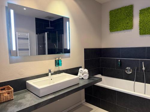 a bathroom with a sink and a tub and a mirror at Apartment Fjordliebe, Lammplatz Bad Krozingen in Bad Krozingen