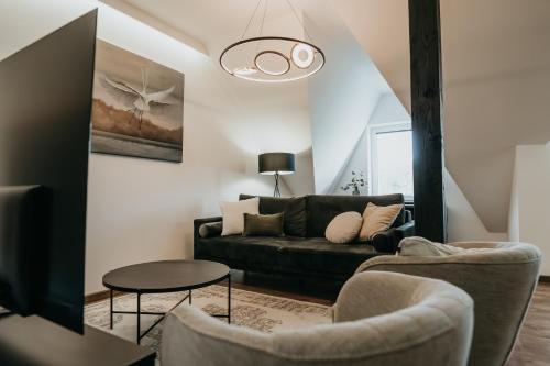 a living room with a black couch and two chairs at Castle Lakes - Apartamenty in Grzymalin