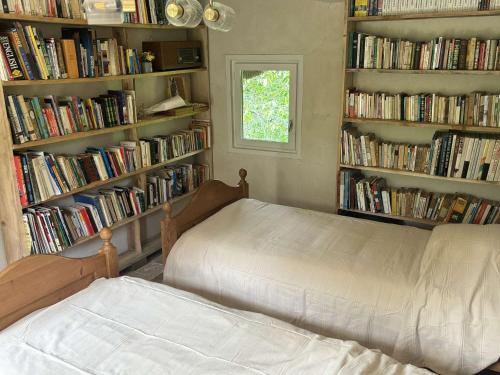 - une chambre avec un lit et des étagères de livres dans l'établissement Chaumière d'écrivain au cœur de la Normandie, à Fiquefleur-Équainville