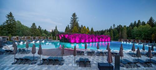 a large swimming pool with chairs and umbrellas at Apartel Skhidnytsya in Skhidnitsa