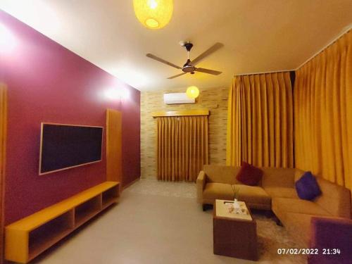 a living room with a couch and a flat screen tv at Rass Resort Gazipur in Gazipur