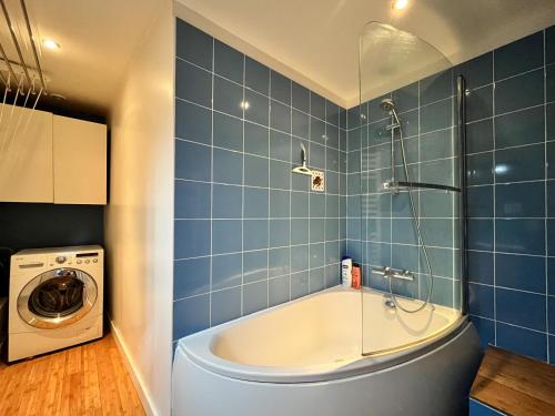 a bathroom with a tub and a washing machine at Loft Évasion aux Portes de Paris in Bagnolet