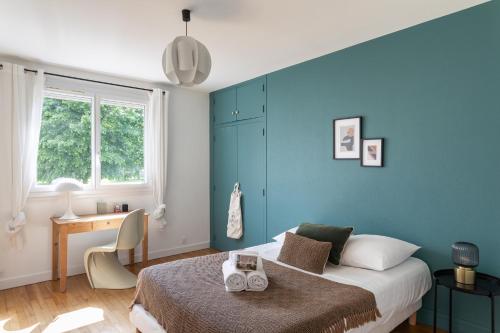 - une chambre avec des murs bleus, un lit et un bureau dans l'établissement Le Montaigne - appt proche de la gare, à Rennes