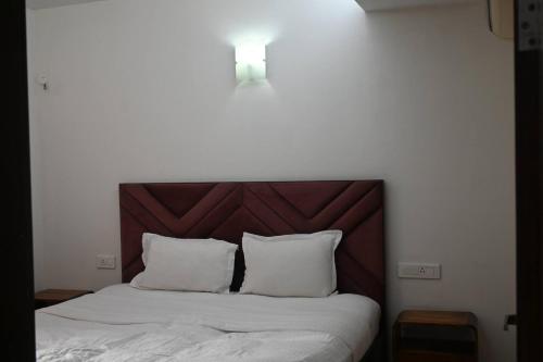 a bed with white sheets and a brown headboard at Luxurious 1BHK Apartment in Gurgaon with Shared Pool and BBQ Area in Gurgaon