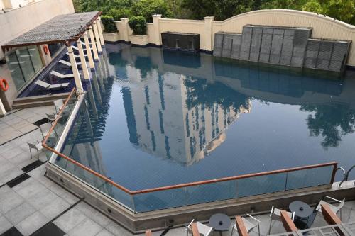 a large swimming pool with chairs and a bridge at Luxurious 1BHK Apartment in Gurgaon with Shared Pool and BBQ Area in Gurgaon