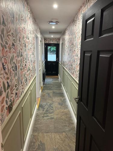 a hallway with a door and floral wallpaper at Victoria Gate Lodge in Derry Londonderry