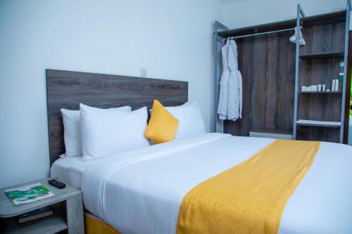 a bedroom with a large white bed with a yellow blanket at KISIMANI ECO RESORT & SPA LTD in Isiolo