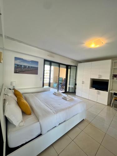 une grande chambre blanche avec un grand lit avec des oreillers jaunes dans l'établissement Studio Palais de la Méditerranée, à Nice