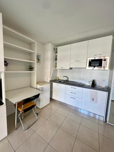 une cuisine avec des placards blancs, une table et un bureau dans l'établissement Studio Palais de la Méditerranée, à Nice