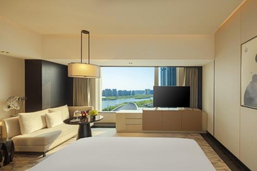 a hotel room with a bed and a couch and a tv at New World Shenyang Hotel in Shenyang