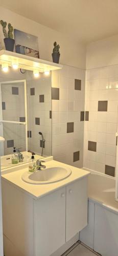 une salle de bain blanche avec un lavabo et un miroir dans l'établissement Le Nid Bleu Confort & Mer à Pied, à Cayeux-sur-Mer