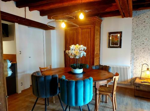 une table à manger avec des chaises et un vase de fleurs. dans l'établissement Le Petit Meslier, à Épernay