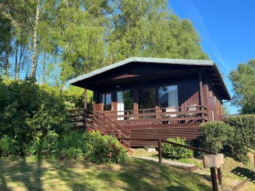 a large wooden cabin with a porch in the grass at Equinox Cabin in Torlundy