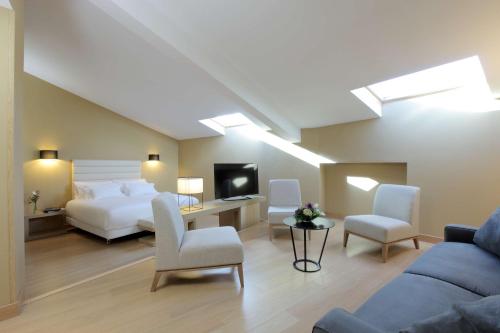 una camera da letto con un letto, un divano e una TV di NH Collection Cáceres Palacio de Oquendo a Cáceres