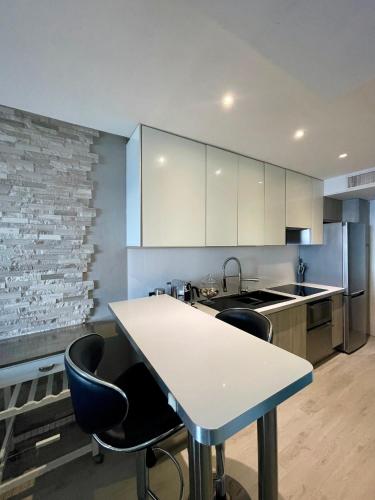 une cuisine avec une table blanche et des chaises noires dans l'établissement Appartement vue mer aux portes de Monaco, à Cap d'Ail