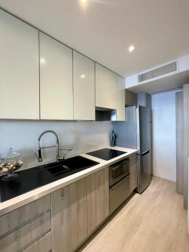 une cuisine avec des armoires blanches et un évier dans l'établissement Appartement vue mer aux portes de Monaco, à Cap d'Ail